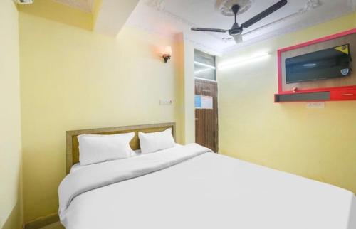 1 dormitorio con 1 cama blanca y TV en POP Oyo Flagship Moon Light Hotel, en Ranchi