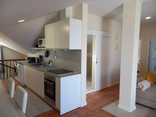 a kitchen with white cabinets and a stove top oven at Casa Dos Ramos in Arco da Calheta