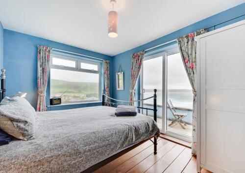 a bedroom with blue walls and a bed with a large window at The Albatross 12 in Woolacombe