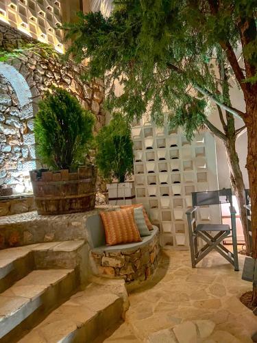 a patio with a couch and a chair and a tree at PortaDelMare deluxe suites in Hydra