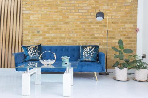 a living room with a blue couch and a brick wall at Legoland Heathrow Windsor Apartment Hotel in Slough