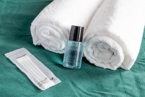 a bottle of one lotion next to a pile of towels at Center of Antwerp, Fully Equipped, Train Station in Antwerp