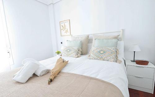 ein weißes Schlafzimmer mit einem großen weißen Bett mit Kissen in der Unterkunft Coqueto apartamento en Liencres. in Liencres