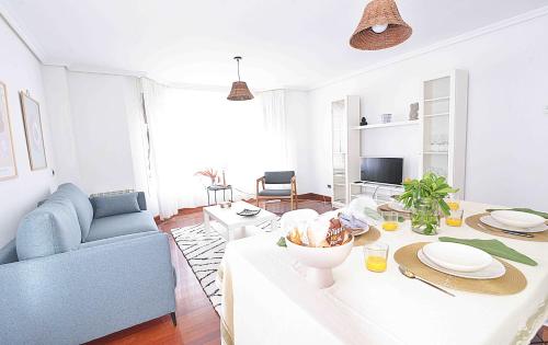 ein Wohnzimmer mit einem Tisch und einem blauen Sofa in der Unterkunft Coqueto apartamento en Liencres. in Liencres