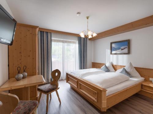 a bedroom with a bed and a desk and a tv at Landhaus Alpenherz in Aschau