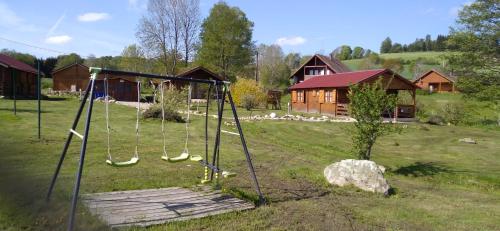 a swing set in a yard with a house at chalets les 5 loups in Gerbépal