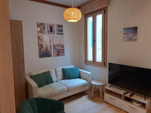 a living room with a white couch and a television at Renovated fully equipped studio for 2 to 4 pers in La Ciotat