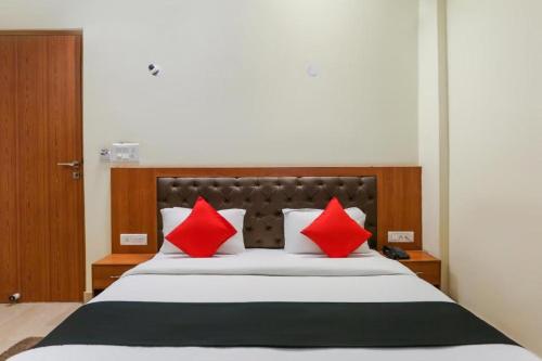 ein Schlafzimmer mit einem großen Bett mit roten Kissen in der Unterkunft Capital O Bvh Hospitality Near Pvr Ansal Plaza Greater Noida in Noida