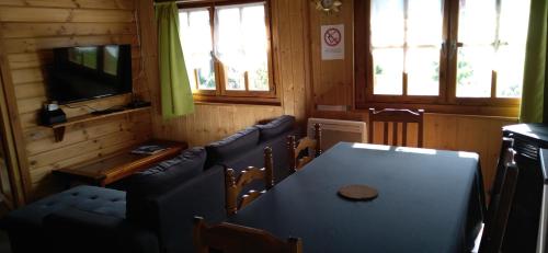 a dining room with a table and chairs and a television at chalets les 5 loups in Gerbépal