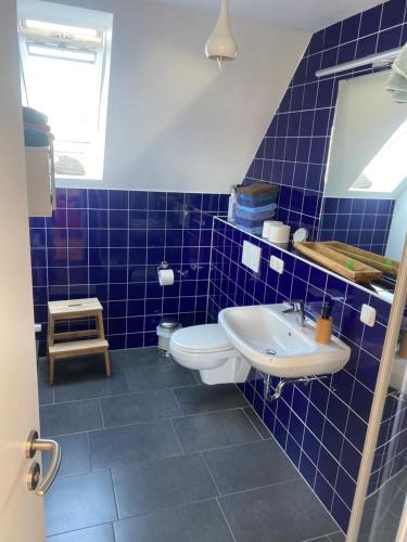 a blue tiled bathroom with a toilet and a sink at Nolte Faarderhuuch 7 in Norddorf