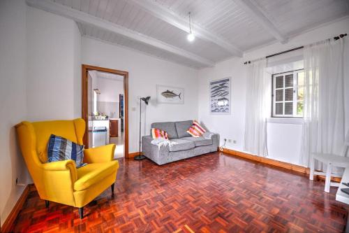 sala de estar con silla amarilla y sofá en CASA do PÁTIO, en Faja Grande