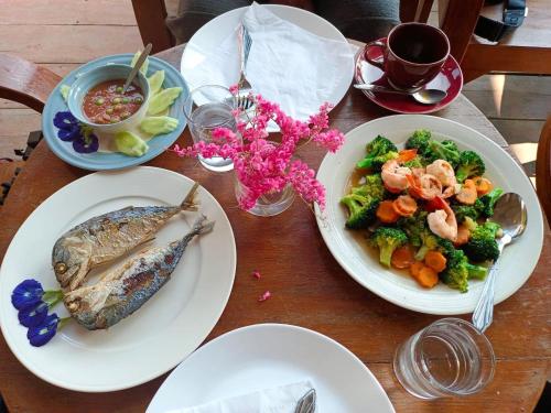 a wooden table with two plates of food and vegetables at DE ROSE Hotel Chiang Mai in Chiang Mai