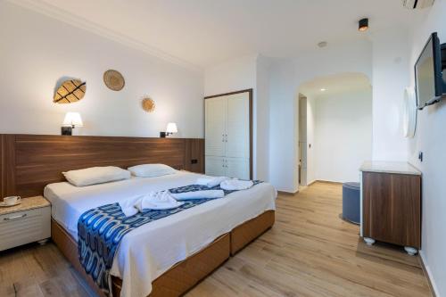 um quarto com uma cama grande e uma televisão em Bronze Hotel em Oludeniz