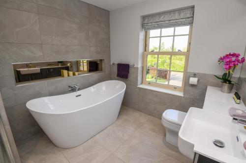 a bathroom with a white tub and a toilet at Sunset View at The Dovecote in Kirkby on Bain