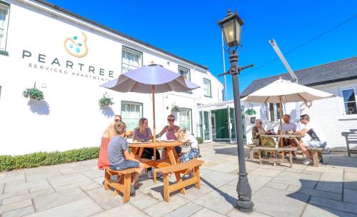 un grupo de personas sentadas en una mesa bajo un paraguas en Peartree Serviced Apartments, en Salisbury