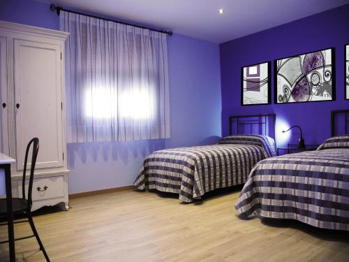 a bedroom with two beds and purple walls at El Balsetón in Peñalba