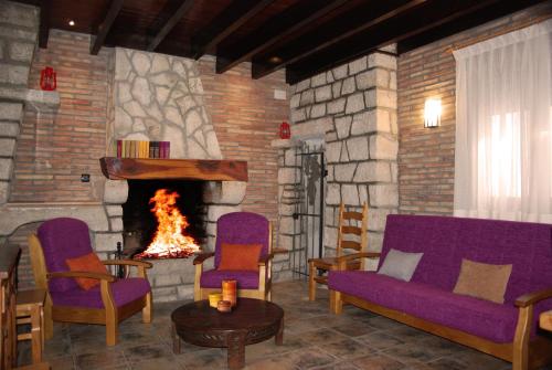 sala de estar con muebles de color púrpura y chimenea en El Balsetón, en Peñalba