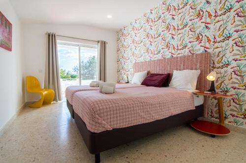 a bedroom with a bed with a colorful wall at Quinta da Felicidade, Casa Estrela in Guia