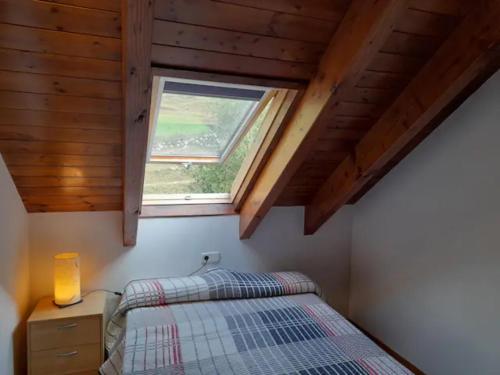 1 dormitorio con cama y ventana en Apartamento abuhardillado con velux erta 3 en Pla de l'Ermita
