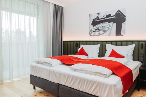 a bedroom with a large bed with red and white pillows at Hotel Das Grambacher 