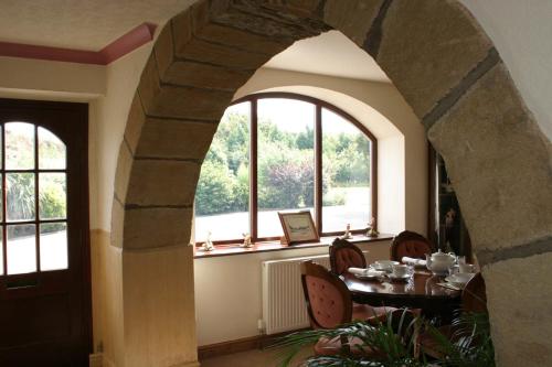 ein Esszimmer mit einem Tisch und 2 Fenstern in der Unterkunft Ackroyd House in Holmfirth