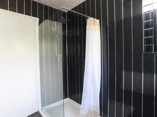 a shower with a white shower curtain in a bathroom at Haddef Penmaenmawr in Penmaen-mawr