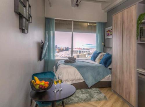 una camera con letto, tavolo e finestra di Executive City Micro Living in Long Street at One Thibault a Città del Capo