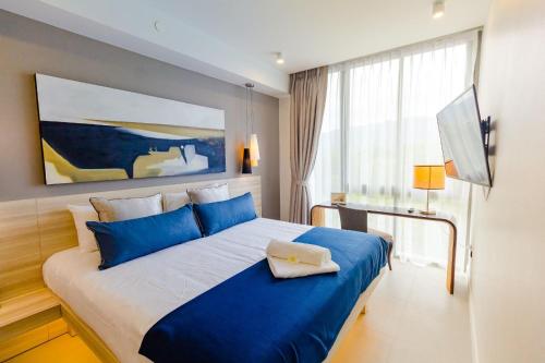 a bedroom with a large bed with blue pillows at OceanStone 1-BR next building view in Bang Tao Beach