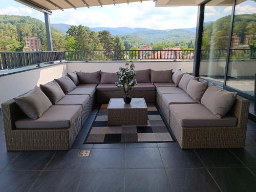 a couch on a balcony with a view of the mountains at Spa Resort & Hotel Vrnjačke Terme in Vrnjačka Banja