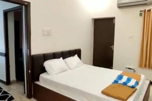 Schlafzimmer mit einem weißen Bett mit einem Kopfteil aus Holz in der Unterkunft Vaishali Beach Villa in Suratakal
