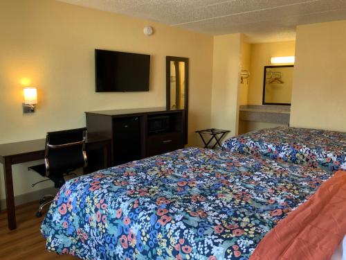 a hotel room with two beds and a desk and a television at Town & Country Inn in Troy