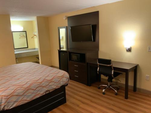 a hotel room with a bed and a desk and a television at Days Inn by Wyndham Troy IL in Troy