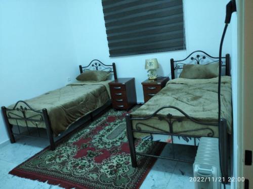 a bedroom with two beds and a rug at بيت ضيافة حنضلة in Bethlehem