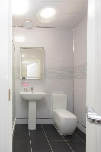 a white bathroom with a sink and a toilet at Legoland Heathrow Windsor Apartment Hotel in Slough