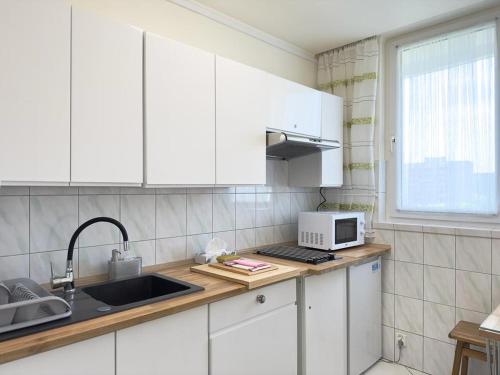 cocina con armarios blancos, fregadero y microondas en Apartament Bazyliańska - 100m do Metra "Bródno", 20 minut do centrum Warszawy en Varsovia