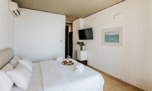 a hotel room with a white bed and a tv at Apollo Resort in Agia Marina Aegina