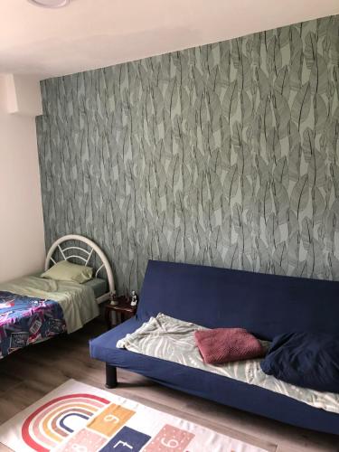 een slaapkamer met een blauwe bank voor een muur bij Ty case péi in Saint-Aignan