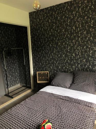 een slaapkamer met een bed met een zwarte muur bij Ty case péi in Saint-Aignan