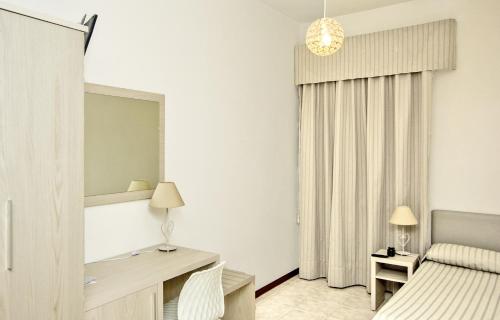 a bedroom with a bed and a desk and a mirror at Hotel Lucerna in Castiglione della Pescaia