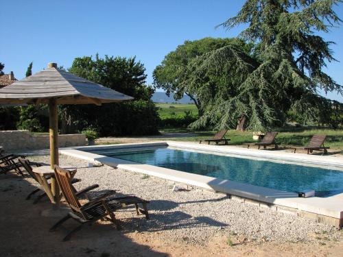 uma piscina com duas cadeiras e um guarda-sol e uma mesa e cadeiras em Domaine du Coffre em Pertuis