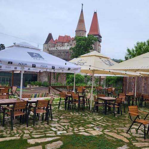 a group of tables and chairs with umbrellas at Pensiunea Hanul Huniazilor HD in Hunedoara