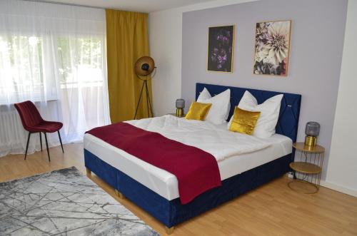1 dormitorio con 1 cama grande con almohadas amarillas y rojas en M&D Apartments nähe Volkspark mit Balkon - Netflix - Küche, en Kaiserslautern