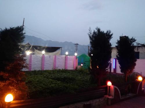 une cour éclairée la nuit avec des lumières roses et violettes dans l'établissement Foreshore Resort, à Srinagar