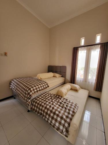 two beds sitting in a room with a window at SAMARA VILLA in Batu