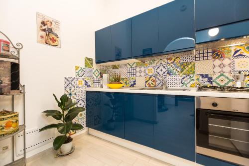 a kitchen with blue cabinets and a tile wall at Colosseum-Apartments in Rome