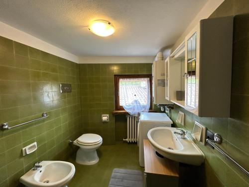 a green bathroom with two sinks and a toilet at Chalet Garda in Peschiera del Garda