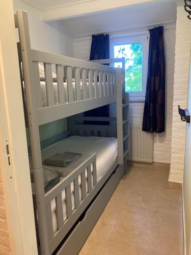 a white bunk bed in a room with a window at Het Karnhuis in Schoondijke