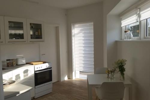 a white kitchen with a table and a window at Cozy and bright apartment in Viby