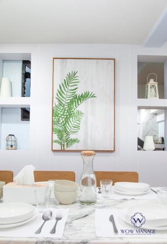 a white dining room with a table with plates and a vase at Enjoy Sunset Rainbow Alley - WOW Townhouse at Patong Hill in Patong Beach