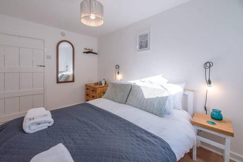 a bedroom with a bed and a table with a mirror at Button Cottage in Wickham Market